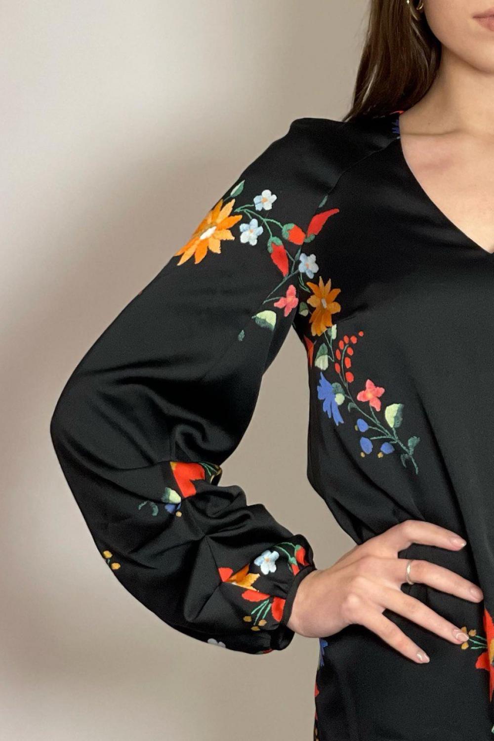 The dress is black with a colorful NocheMio print